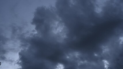 Wall Mural - Time lapse of dark gray clouds churning in a late day blue hour colored sky
