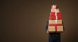 © Volha - Child carrying stack of colorful Christmas presents on brown background