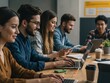 © Sergey - A diverse group of young professionals smiling and working collaboratively on laptops and tablets at a wooden table in a modern office.