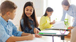 © Home-stock - Positive European schoolgirl helping friend with task, pointing at boy's copybook, sitting near at desk in classroom of private school during lesson