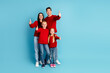 © deagreez - Cheerful family posing in matching red outfits on a bright blue background, radiating joy and unity during festive moments