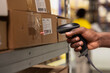 © DC Studio - Close up of black worker scanning the barcode awb tags on cargo boxes, registering the merchandise and shipment details before distribution. Using scanner on tracking numbers in depot.