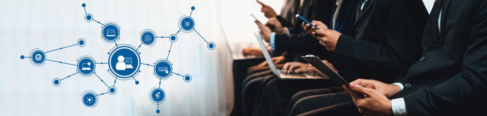 A group of business professionals engaged in using their smartphones and laptops in an office environment, showcasing digital connectivity and modern communication trends. Amity