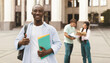 © Prostock-studio - Happy african american student guy standing outdoors with his classmates in university campus, posing and smiling to camera. Study after covid-19 quarantine concept