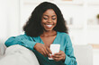 © Prostock-studio - Cheerful pretty millennial black woman in casual outfit chilling at home with smartphone, chatting with guys on newest dating mobile application, sitting on couch, copy space, closeup