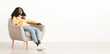 © Prostock-studio - Relaxed pretty millennial black woman in casual with bushy hair sitting at comfotrable arm chair with cup of herbal tea over white empty wall, looking at copy space and smiling, panorama