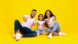 © Prostock-studio - Happy Middle-Eastern Family Of Three Gesturing Thumbs Up Smiling To Camera Approving Something Together Sitting Over Yellow Studio Background. We Like It Concept