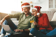 © Prostock-studio - Mature Couple Shopping Online Buying Christmas Gifts Using Credit Card And Laptop Sitting At Home. Happy Customers Wearing Santa Hats Purchasing Presents During Winter Holiday Sales Season