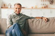 © Prostock-studio - Contented Senior Man Sitting On Sofa At Home, Smiling Looking At Camera. Retired Male Relaxing On Couch In Modern Living Room Indoor On Weekend. Retirement Lifestyle, Domestic Comfort Concept