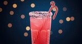 Festive pink cocktail with candy cane garnish on dark bokeh background