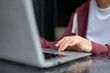 © bongkarn - Close up of a man student's hand typing or tapping on laptop at shiny black table in cafe or library