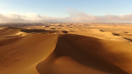 Wall Mural - Shifting cloud shadows and light play across desert dunes timelapse golden light, dynamic, light play