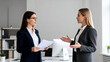 © Emily - Two women in business attire discussing documents