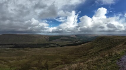 Wall Mural - Expansive view across the Brecon Beacons National Park on the walk up to Pen y Fan, showcasing vast rolling hills, dramatic clouds, and sunlight breaking through over the scenic Welsh landscape.