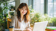 © zaki - 明るいオフィスでノートパソコンを使う笑顔の日本人ビジネスウーマン - Smiling Japanese businesswoman working on laptop in bright modern office