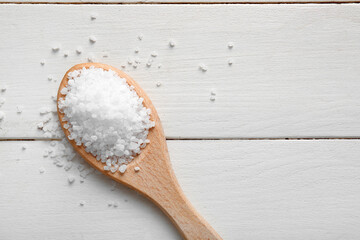 Wall Mural - Spoon of sea salt on light wooden background, closeup