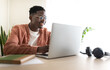 © Daniel - Smiling young man working from home office using laptop computer