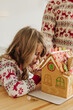 © Cavan Images - Young girl decorates gingerbread house with frosting in kitchen