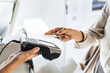 © Koldo_Studio - Customer making a payment using a credit card with contactless technology at a pos terminal. Transaction on a counter