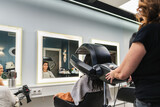 Professional hairdresser drying a female client's wet hair using a modern hair dryer machine in a beauty salon