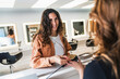 © Koldo_Studio - Happy woman smiling, completing a contactless payment using a credit card and pos terminal at a hairdressing salon