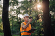 © Ljustina - Forestry engineer inspecting trees using mobile phone and clipboard in forest