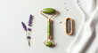 © Igor - Jade roller, lavender flowers, and wooden comb on white background