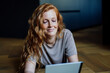 © Westend61 - Smiling woman using tablet PC lying on floor at home