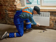 © master1305 - Technician installing white electric convector heater on brick wall indoors. Concept of energy efficiency, utility services, and winter comfort for residential heating materials and media use.