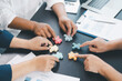 © doidam10 - Business teamwork concept with people holding wooden puzzle pieces together, symbol of collaboration, strategy, problem solving, partnership and corporate success in modern office. business teamwork.