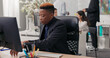 © ABCreative - An office worker sits at his desk in front of a computer, participating in a video call through a webcam. He shows a paper billing document to a co-worker and explains the details.