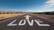 © LIS - A scenic road extends toward distant mountains with LOVE painted in white across two lanes and an upward-pointing arrow