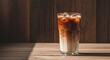 © mlangsen - Tall glass of layered iced coffee on a sun-dappled wooden table with wood paneling