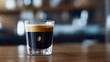 © Risa - Espresso shot in a glass, layered with crema, on a wooden bar top