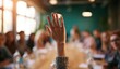 © AndyAziz - Person raising hand in a classroom or meeting room with attentive audience