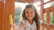 © Monkey Business - Portrait Of Smiling Young Girl Climbing On Equipment In Playground