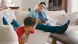 © Monkey Business - Father Sitting On Sofa At Home With Digital Tablet As Son Uses Laptop