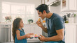 © Monkey Business - Father In Kitchen At Home Eating Cupcakes Baked By Daughter