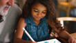 © Monkey Business - Close Up Of Grandfather With Granddaughter Drawing On Digital Tablet At Home