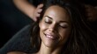 © Thares2020 - A peaceful woman smiles with closed eyes during a relaxing head massage in a softly lit indoor setting