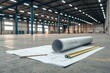 © Khatyjay - Architectural plans and a rolled blueprint resting on the floor of a spacious, empty warehouse