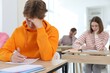 © New Africa - Students taking exam at wooden table indoors, selective focus
