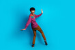 © deagreez - Trendy young man in colorful outfit posing playfully on vibrant blue background, expressing energy and a retro fashion vibe