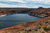 Aerial view of the Glen Canyon Dam and car bridge on the Colorado River in Arizona, USA. Impressive hydroelectric structure surrounded by red sandstone cliffs and desert landscape. 