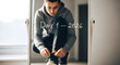 © Pink Zebra - man in a hoodie tying his sneakers in front of a mirror with Day 1 - 2026 written on it. New year fitness resolution and fresh start