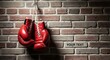 © Ulum - Red boxing gloves hanging on a rustic brick wall symbolizing strength and combat sports.