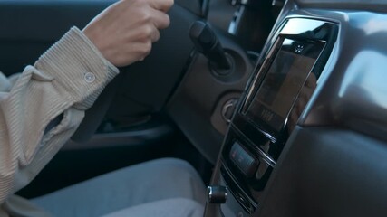 Woman driving a modern car and using the touch screen navigation system, adjusting settings and selecting options while holding the steering wheel