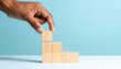© Nashihal - Business concept growth success process, Close up Woman hand arranging wood block stacking as step stair on paper blue background, copy space.