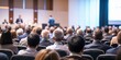 © VistaVisions - Rear view of people in audience at the conference hall, Speaker giving a talk in conference hall at business event.