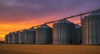 © PixelNova - Dramatic sunset illuminates grain elevators on the golden wheat field, showcasing the heartland's agricultural industry and the beauty of rural America at twilight